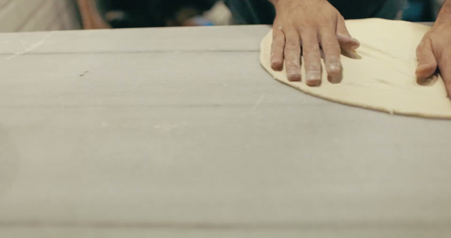 Fresh pizza dough being stretched by hand