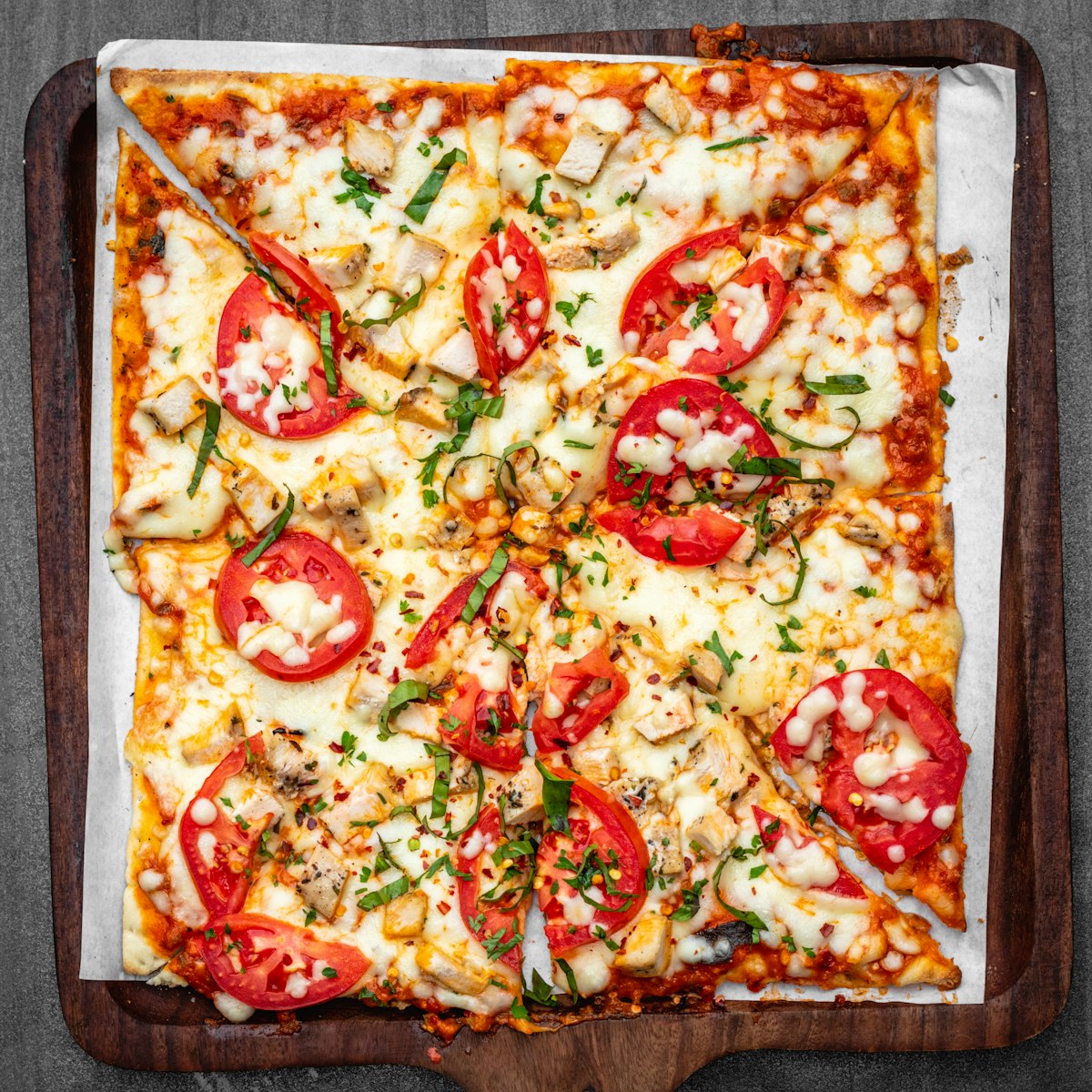 Roman-style square-cut sheet pizza with tomato and basil